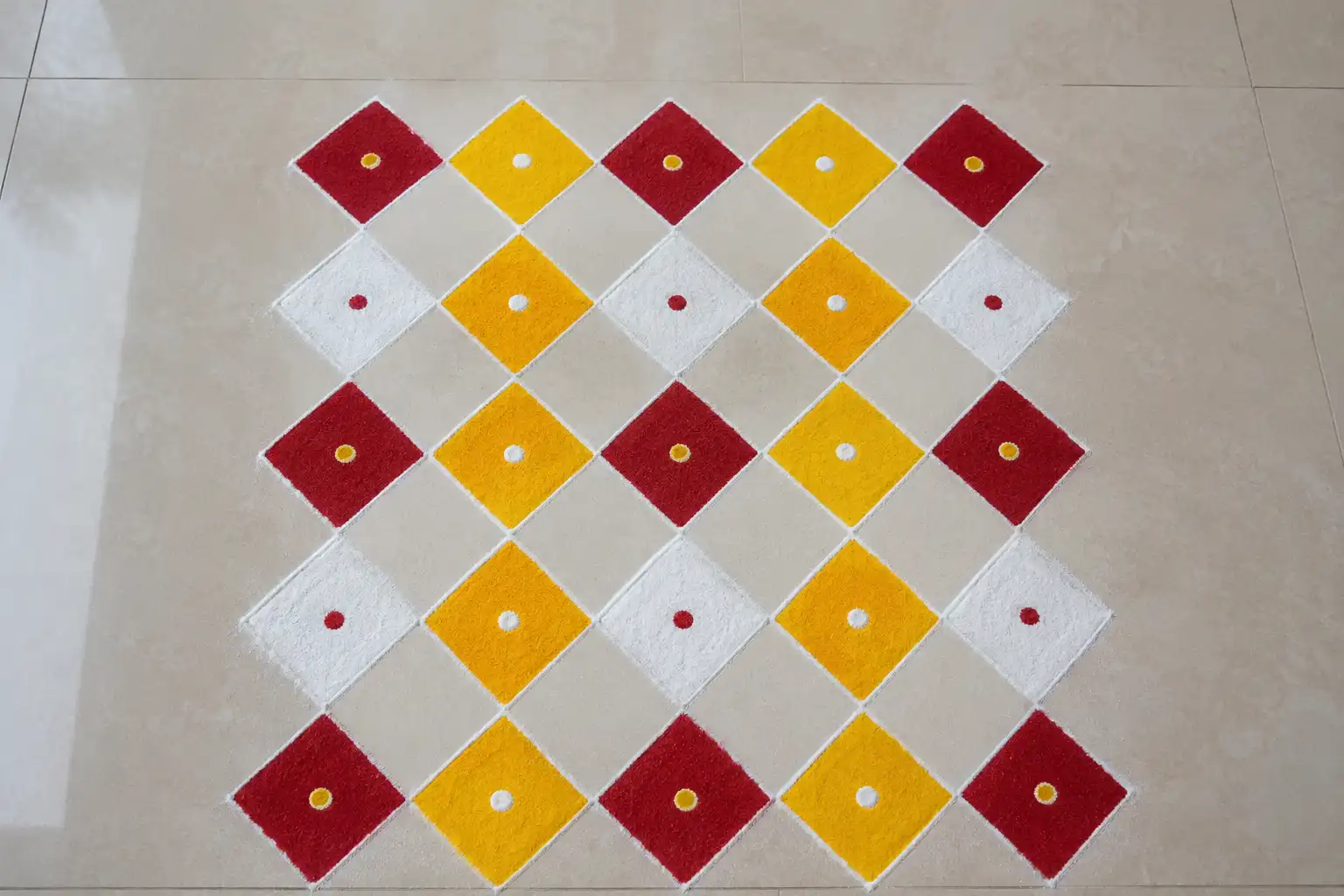 Diamond grid rangoli pattern in red, yellow, and white