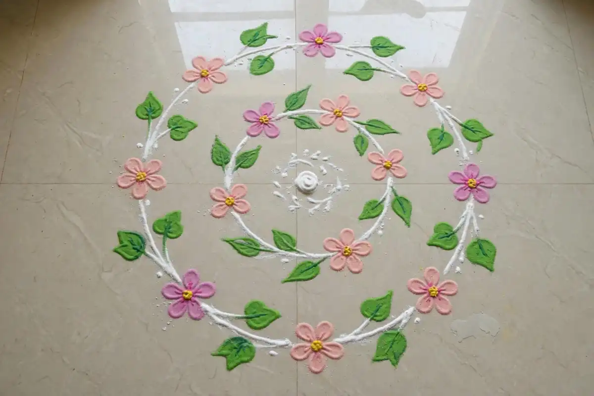 Flowing vine spiral rangoli with leaves in pink and green