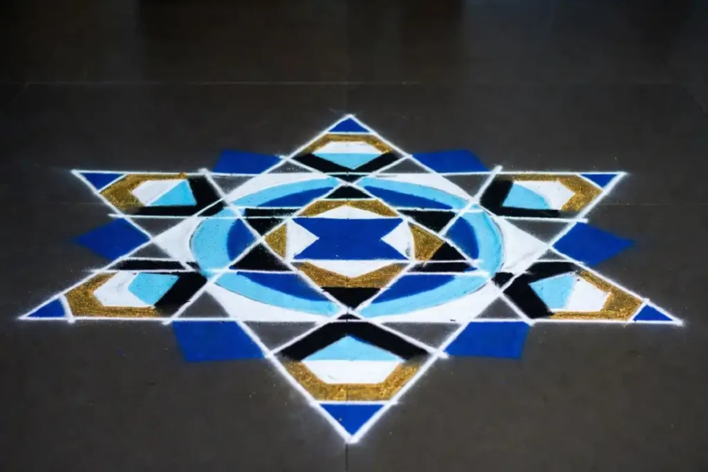 Aesthetic rangoli design with geometric shapes and bright colors on floor