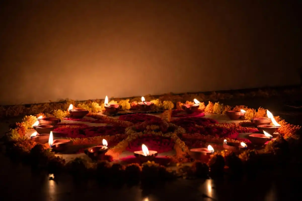 Dhanteras rangoli with marigold petal border and lit diyas at home entrance