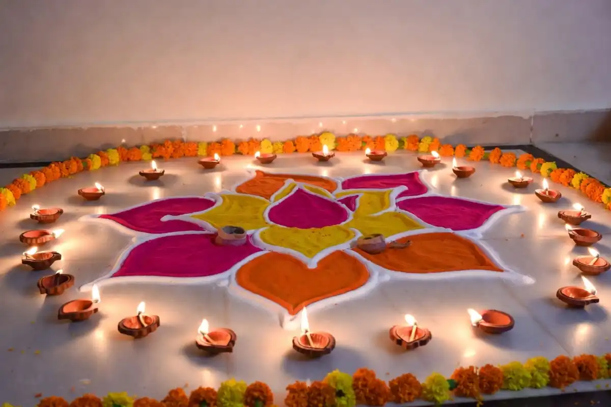 Colorful lotus rangoli design for Dhanteras with diyas and yellow marigold border