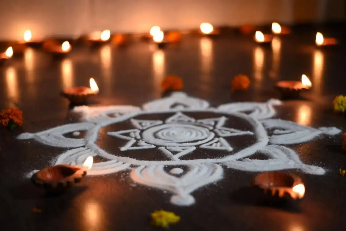 Diwali rangoli decorated with fresh flowers and oil lamps at night