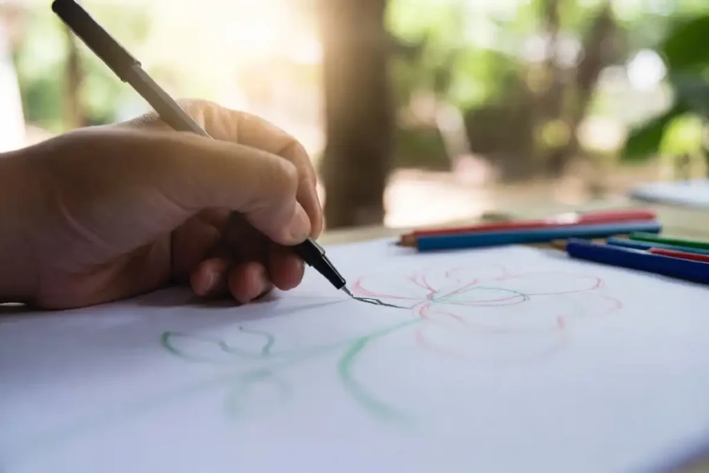 Hand drawing a floral pattern with flowers and leaves on paper