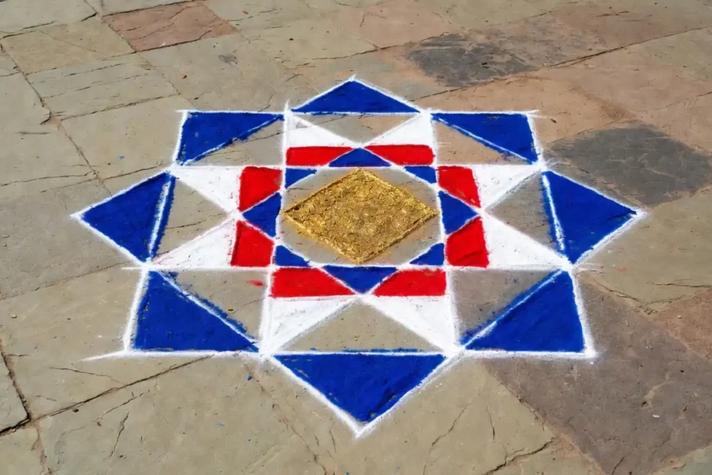 Completed geometric drawing rangoli with diamond and square layers in red, white, blue, and gold