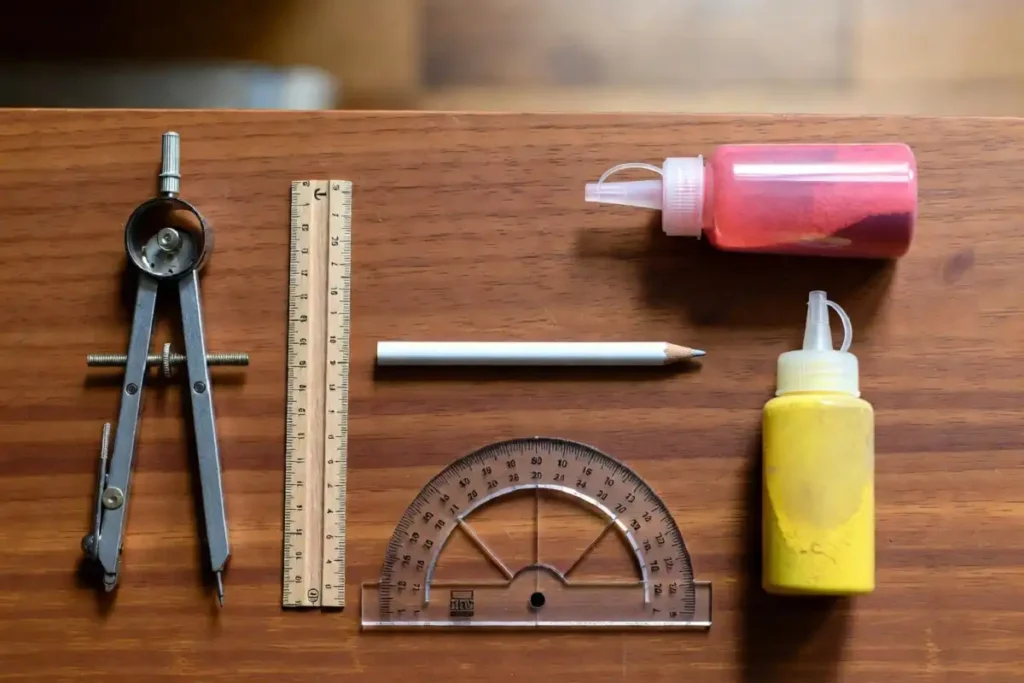 Rangoli tools for geometric drawing including compass, ruler, chalk pencil, and colored powder bottles