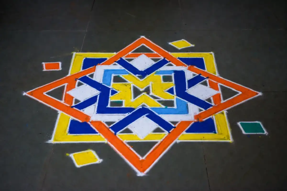 Symmetrical geometric rangoli design with triangles, hexagons, and diamond shapes in vibrant colors