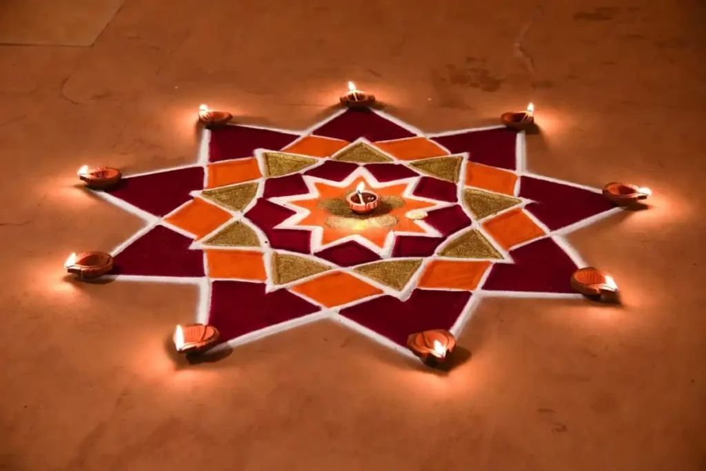 Diwali geometric rangoli with star pattern, diyas, and deep red and gold colors on a terracotta floor
