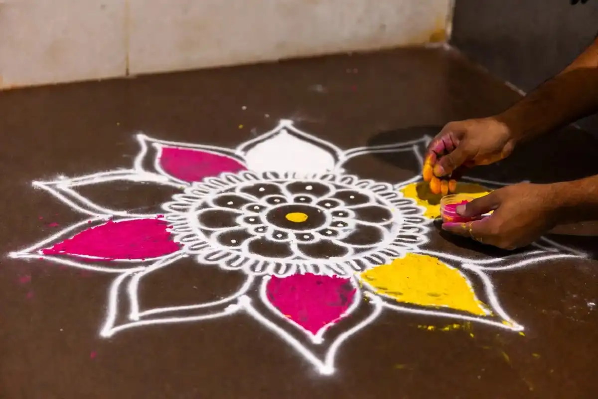 Step-by-step lotus rangoli design creation process showing chalk outline and colored powder petals