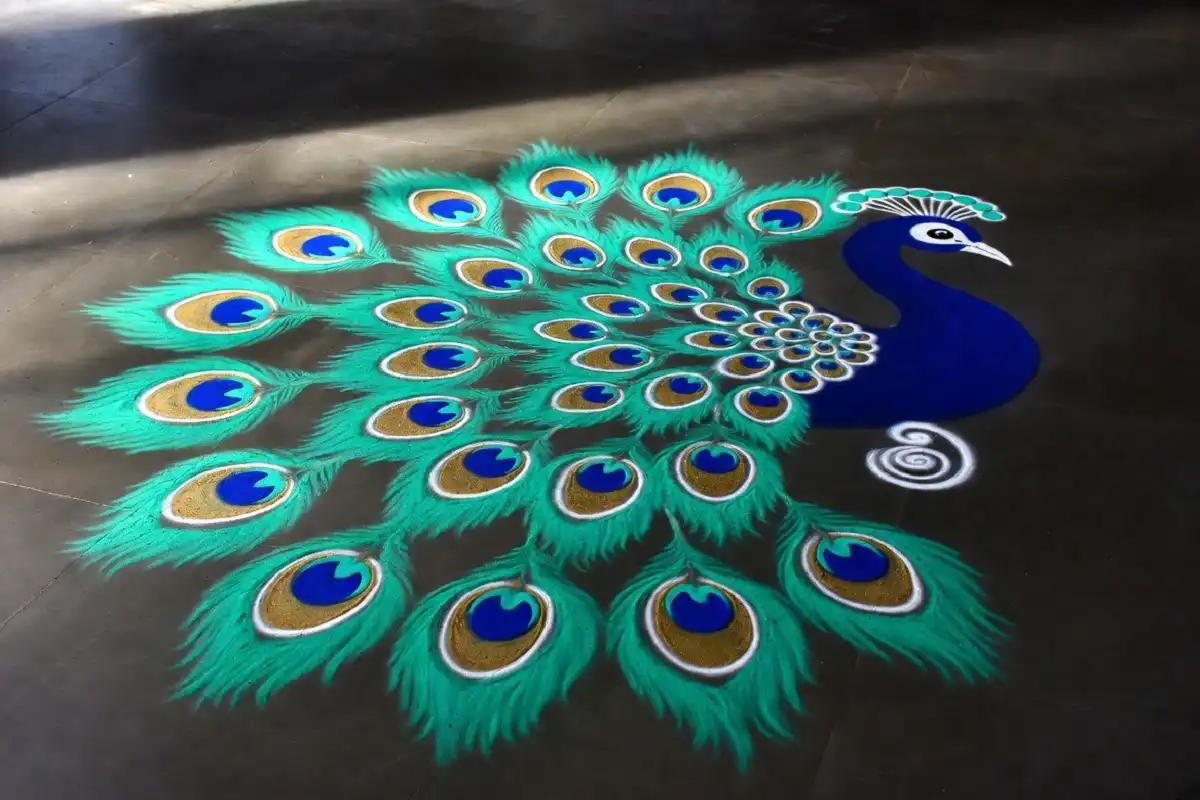 Colorful peacock rangoli design easy to recreate with teal and gold feather patterns on a dark floor