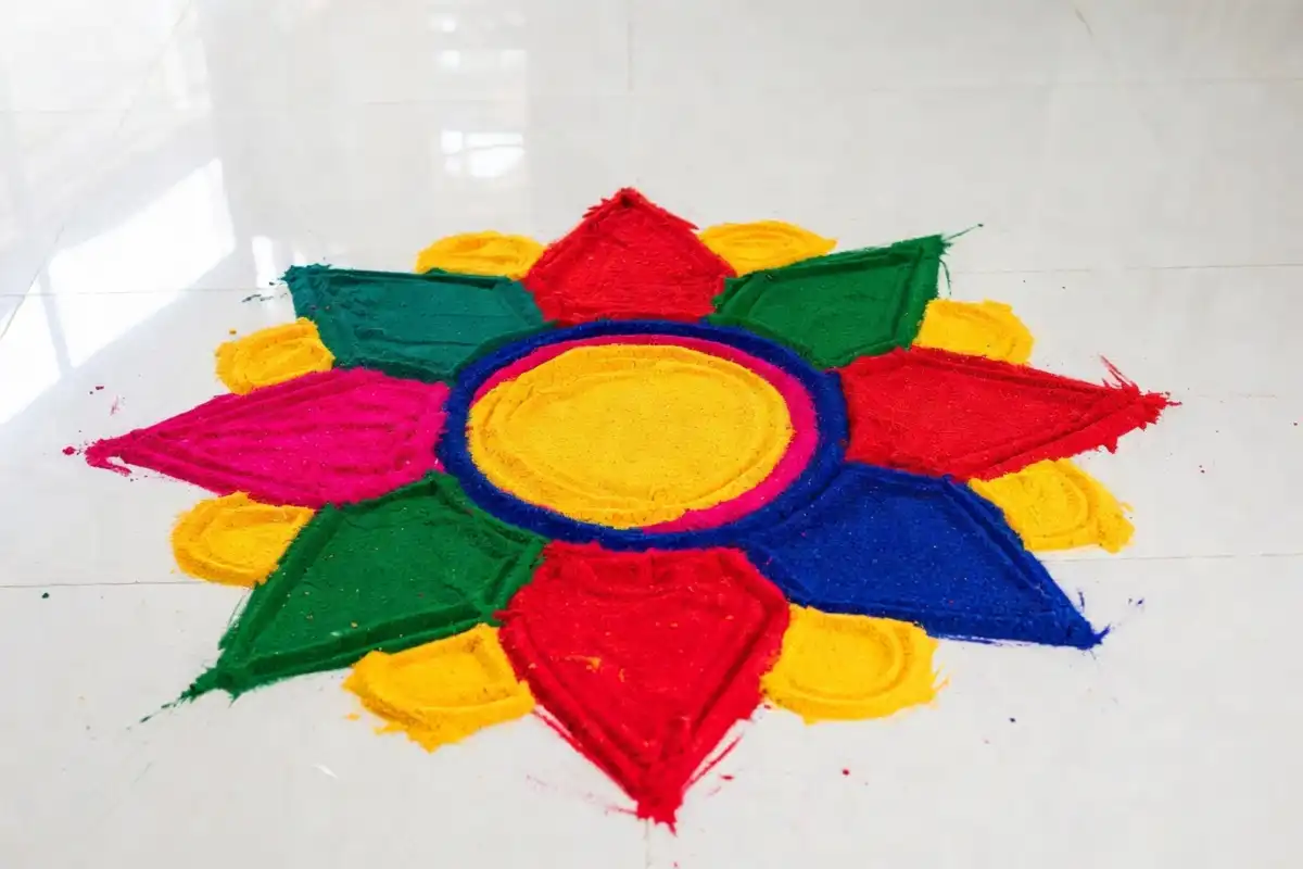 Simple and colorful rangoli design easy floral pattern with petals and circular center on white floor