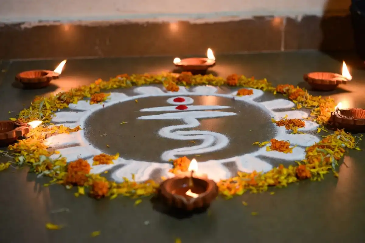 Traditional rangoli design for Dhanteras featuring Lakshmi footsteps with marigold petals and diyas