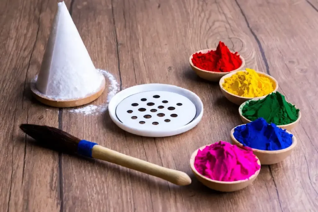 Rangoli tools including dot stencil, powder cone, and colored powders arranged on a wooden surface