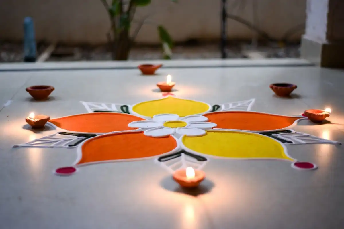 Simple and easy rangoli design for Dhanteras made using stencil with orange and yellow dry colors