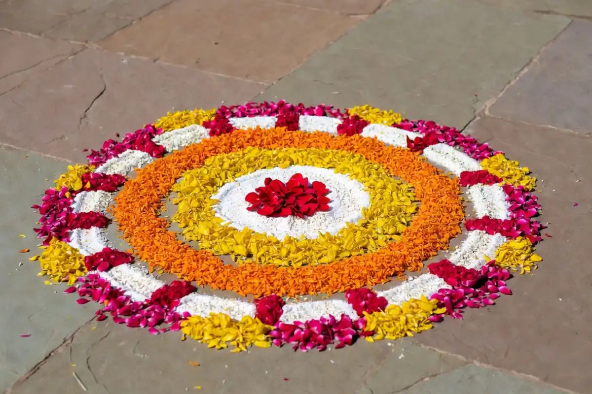 Simple circular rangoli design with flower petals and colored powder in red, yellow, and white