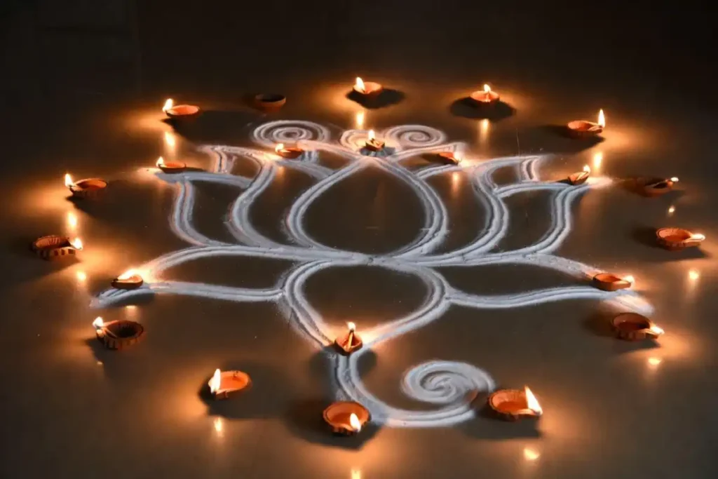 White rangoli design with diya lamps placed around the pattern during Diwali