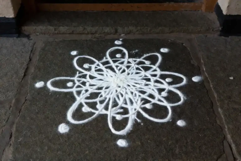 Traditional white rangoli design made with rice flour at a home entrance