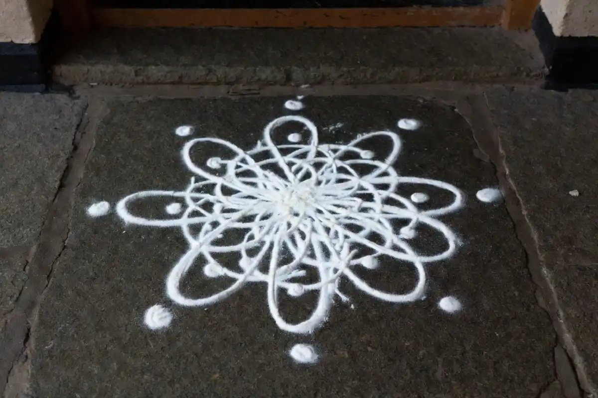 Traditional white rangoli design made with rice flour at a home entrance