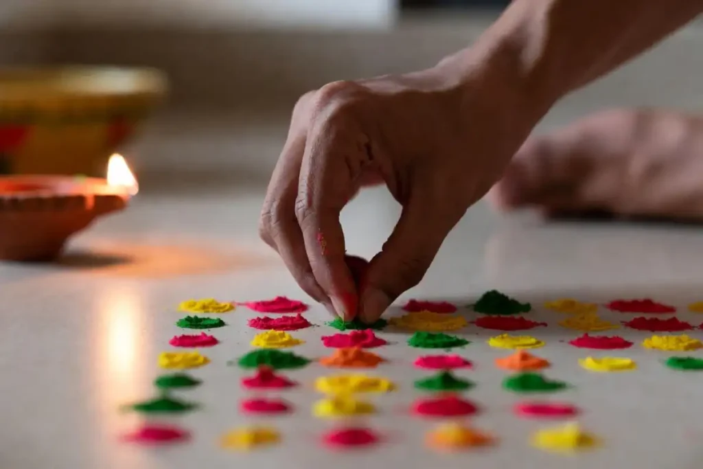 Beginner placing colored powder on rangoli dot grid pattern on floor