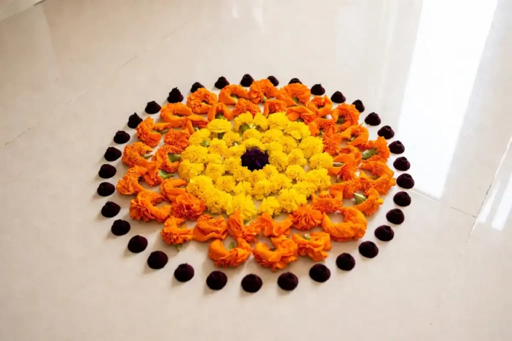Round marigold flower rangoli design in orange and yellow with a dotted border