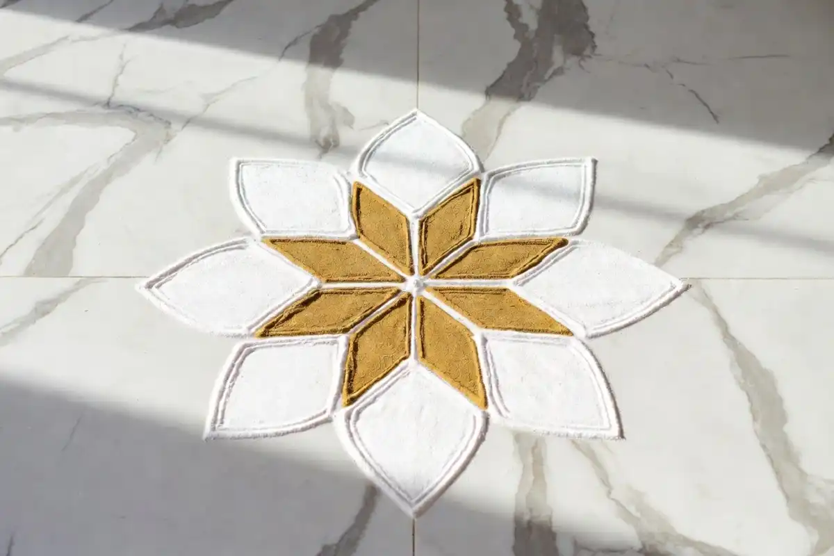 A beautiful minimal rangoli design with soft geometric petals on a white marble floor