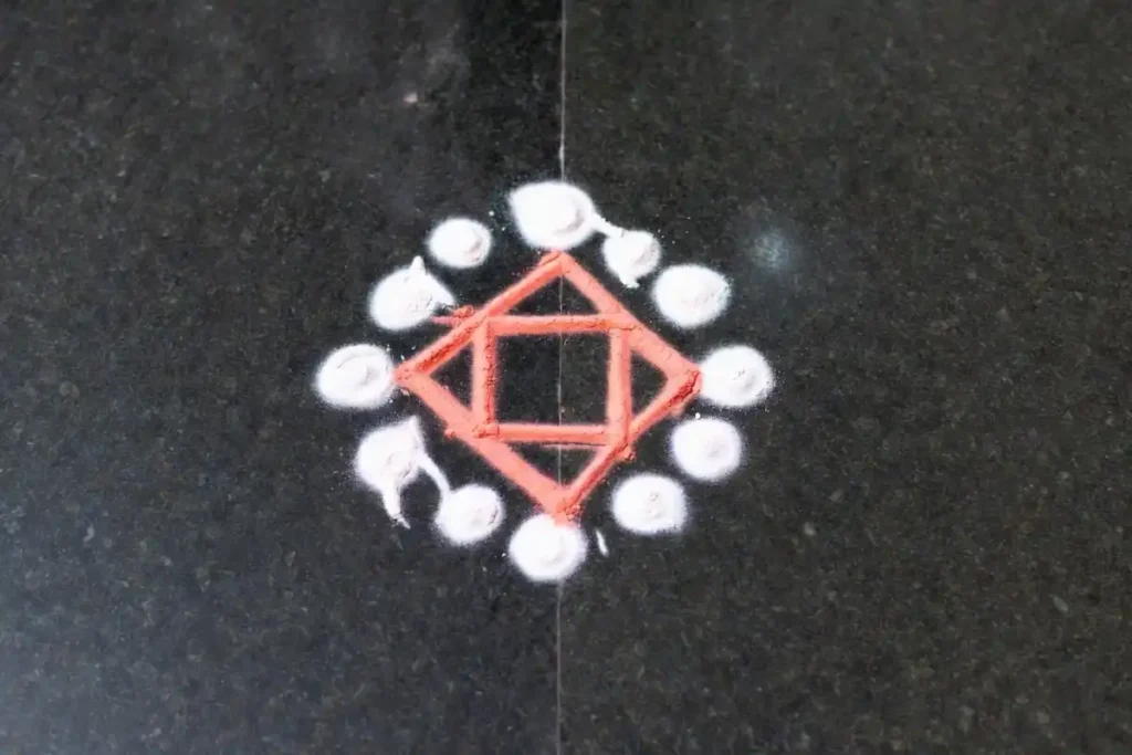 A two-color minimal rangoli design with coral and white geometric star pattern