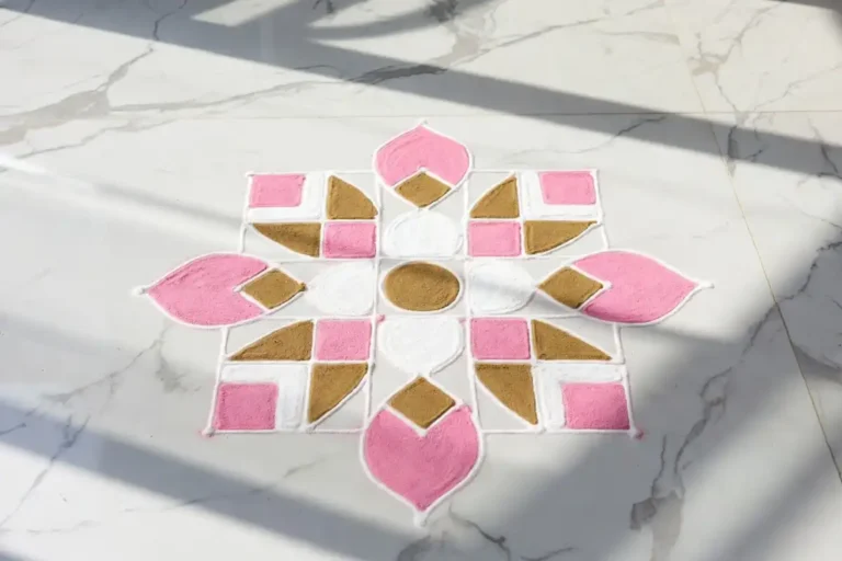 Modern simple rangoli design with geometric shapes in pink, white, and gold on marble floor