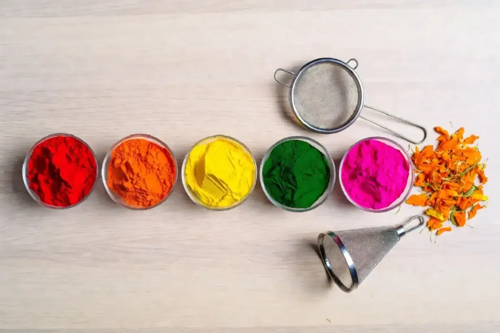 Bright rangoli colour powders, a sieve, and marigold petals for Navratri