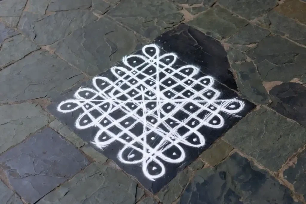 Simple kolam dot grid pattern with interlocking loops on a stone floor