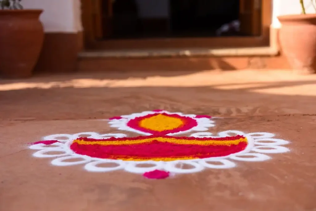 Small diya rangoli design at a home entrance with warm colors