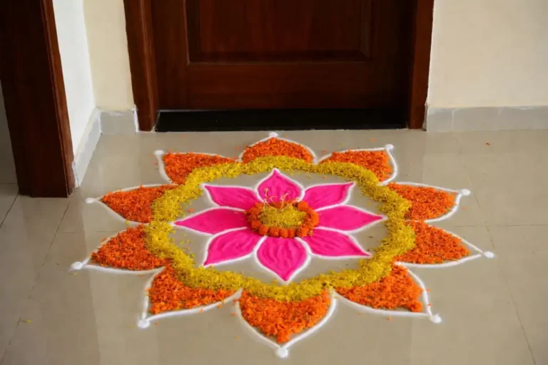 Colorful small flower rangoli with lotus and marigold petals at a home doorway