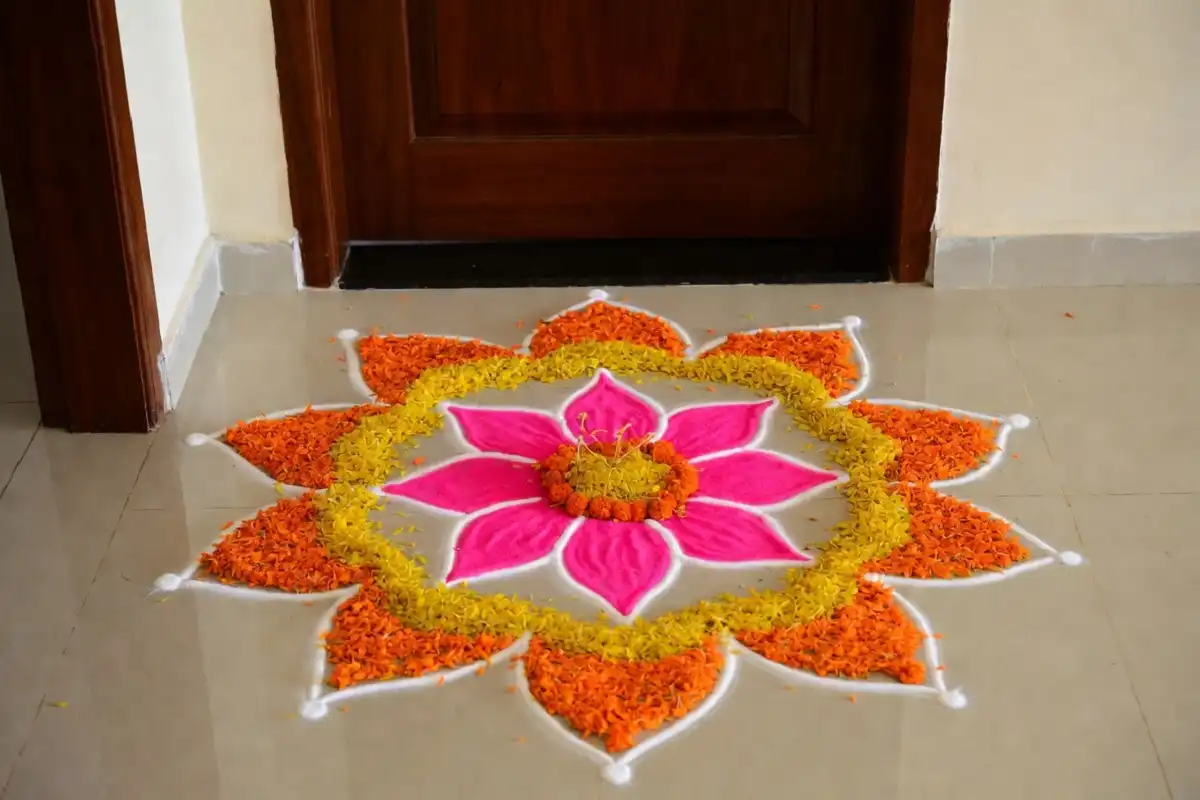 Colorful small flower rangoli with lotus and marigold petals at a home doorway