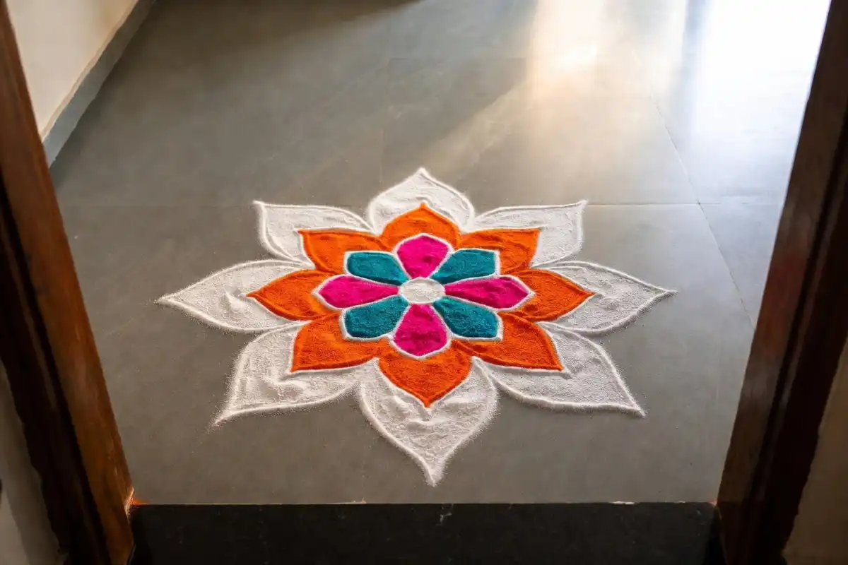 Small symmetry rangoli with balanced flower petals at a home doorway