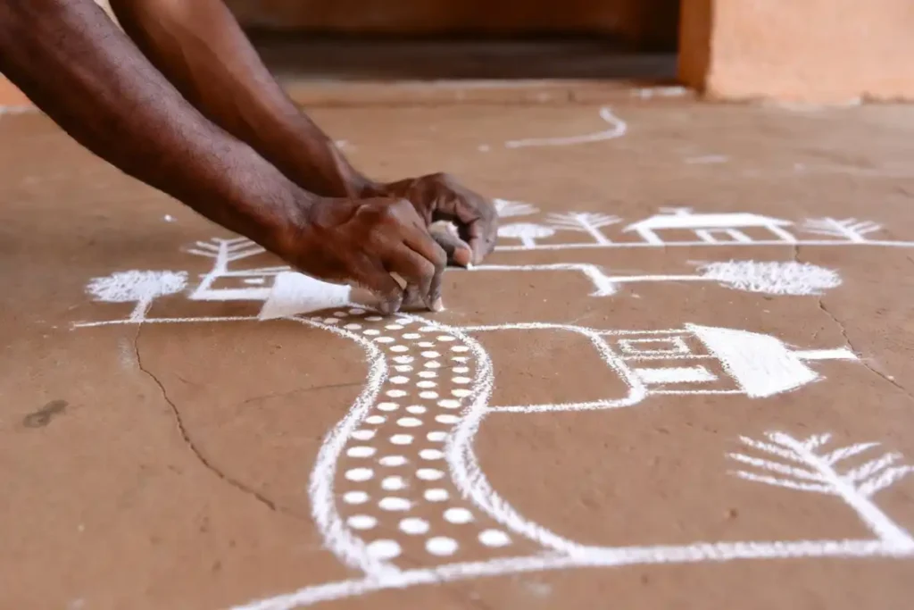 Hands drawing easy village rangoli step by step on a traditional floor