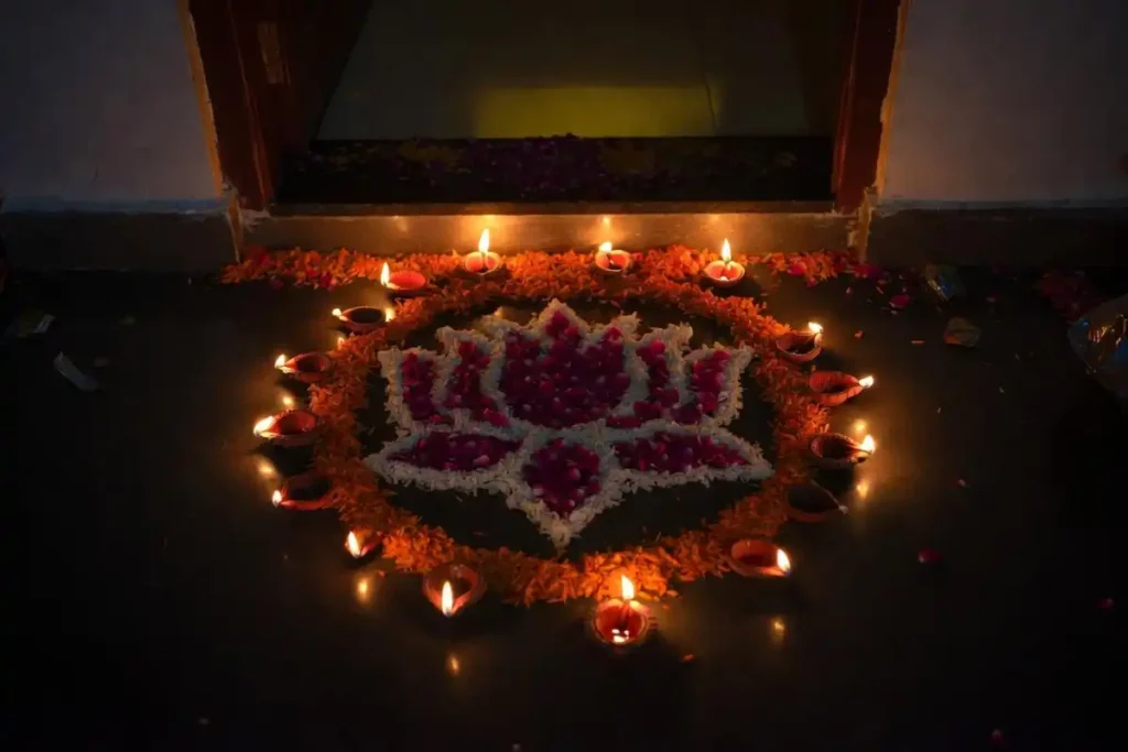 Diwali rose petal rangoli ideas featuring a lotus center, marigold border, and lit diyas