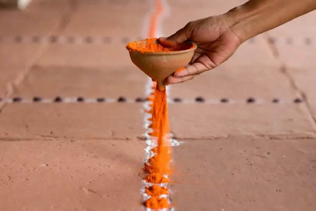 Person using a funnel to create festival rangoli for beginners at home