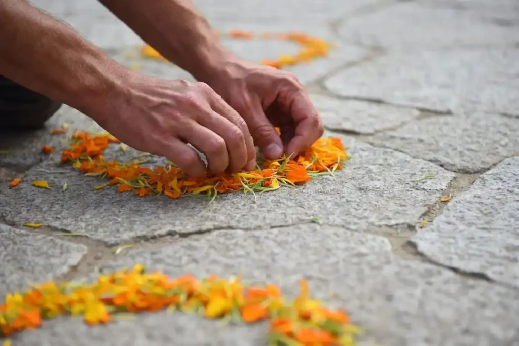 Close-up of hands building Onam rangoli designs petal by petal