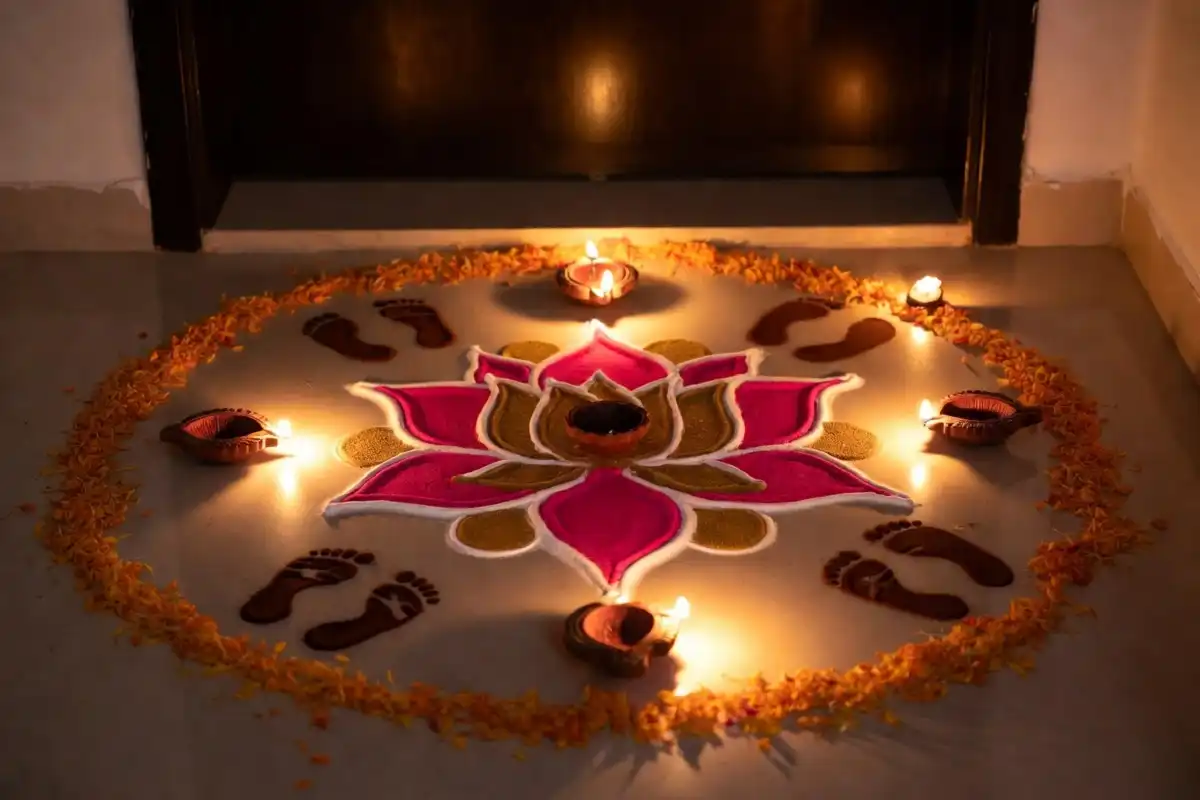 Diwali lotus rangoli design with diyas and Lakshmi footprints at a home entrance