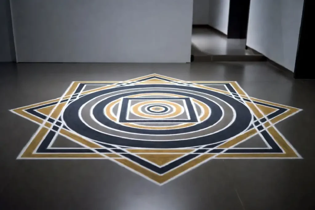 Concentric circle and square geometric rangoli in grey and gold at an office reception