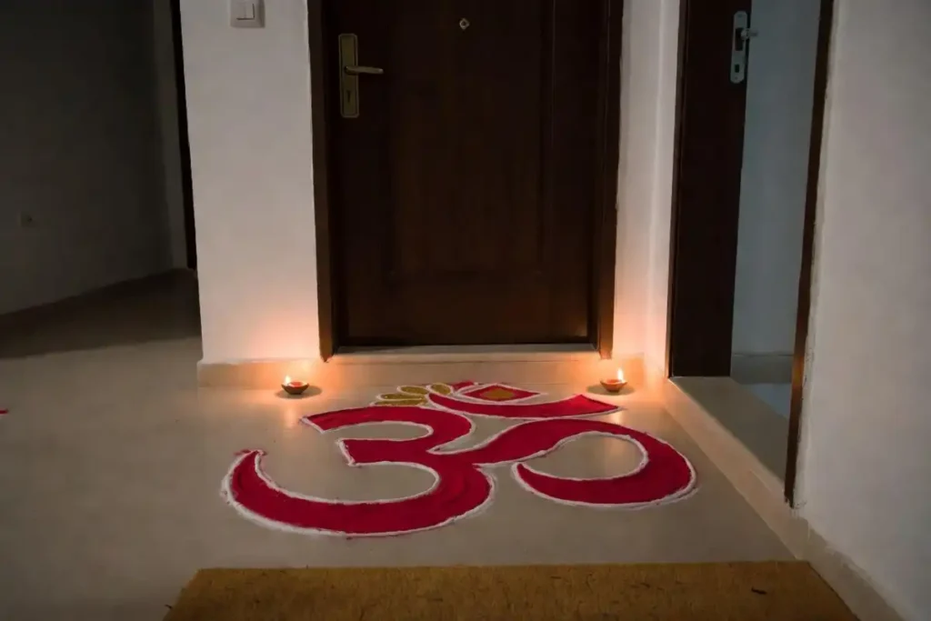 Om symbol rangoli design at a home entrance decorated with diyas