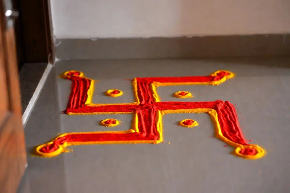 Swastik rangoli in red and yellow, a traditional Indian symbol of good fortune, drawn at an entrance