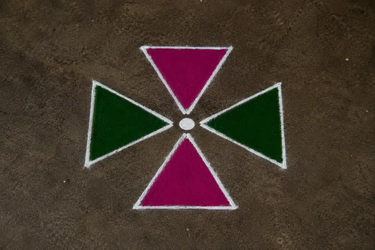 Colorful four-triangle rangoli with white outlines forming a symmetrical star pattern