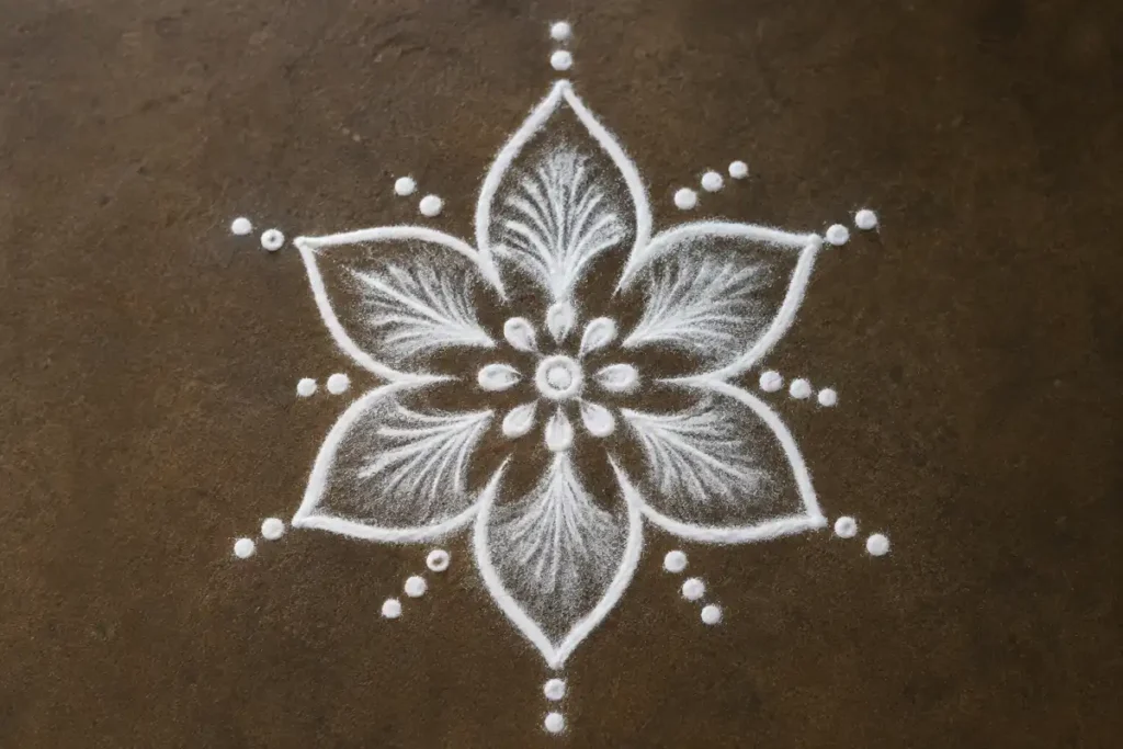 Simple white flower rangoli design made with rice flour and decorative dots